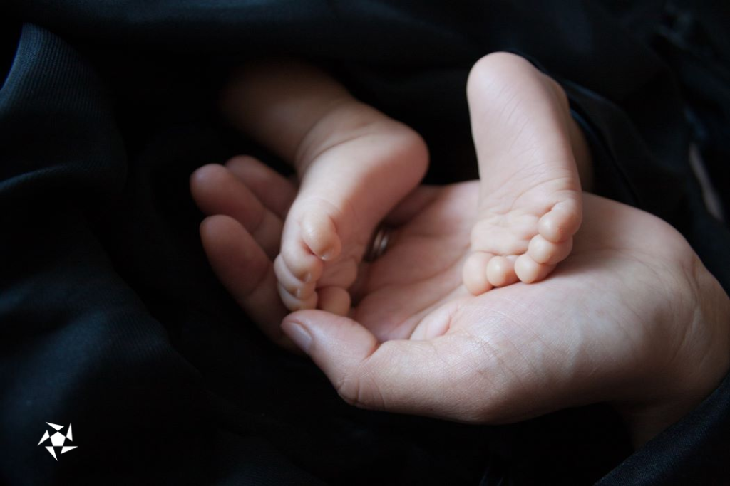 The two little feet of a newborn baby in its mother's open hand