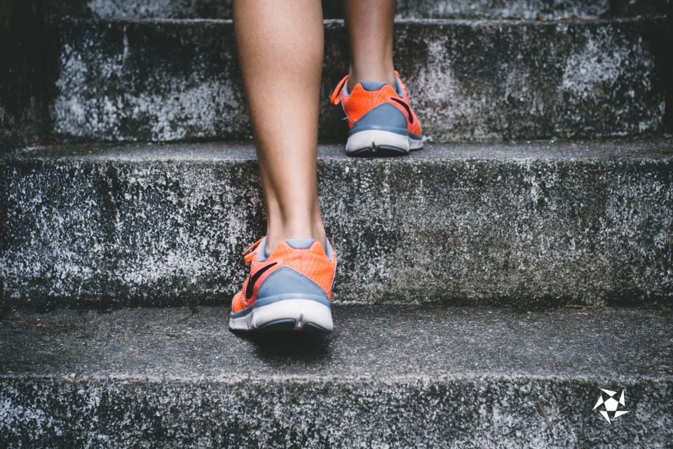 A young woman in orange-grey sneakers climbing a staircase